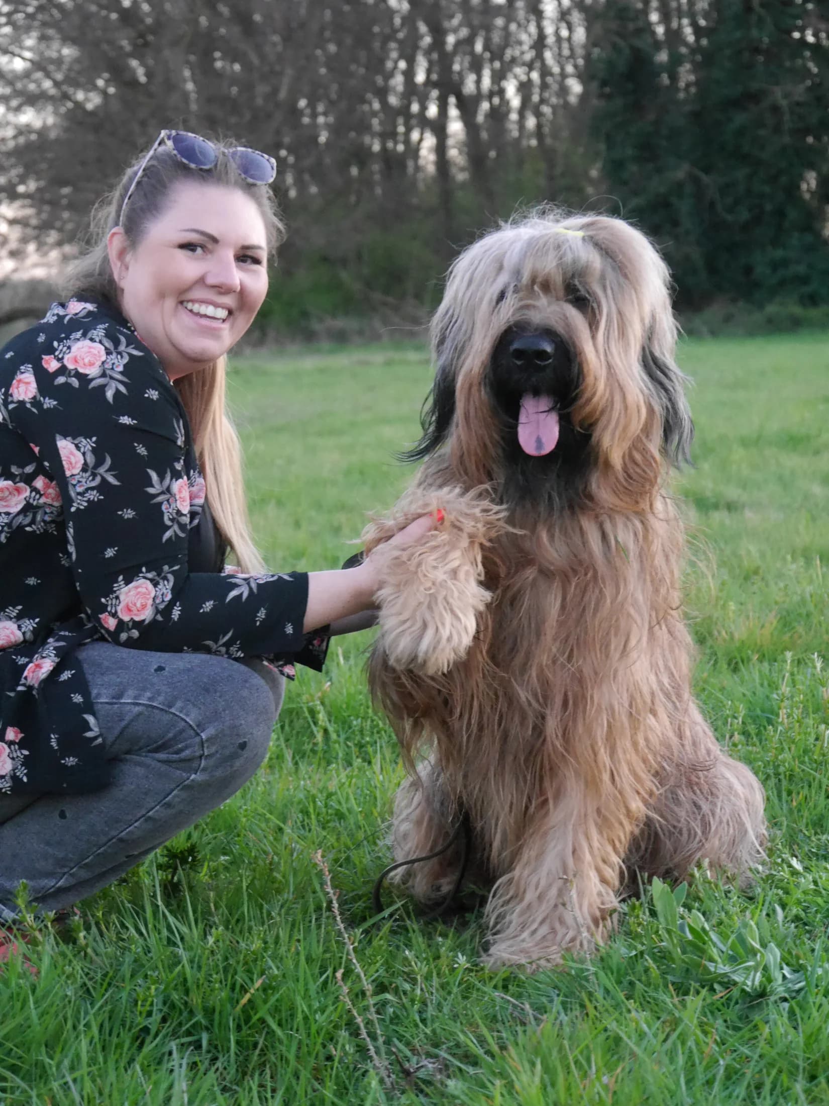 Lachende Frau hält die Pfote eines flauschigen Hundes